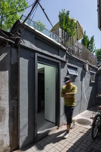 A modern, minimalist residential exterior with concrete walls and a glass door.