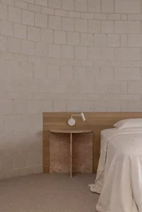 A minimalist bedroom with a wooden headboard and white bedding.