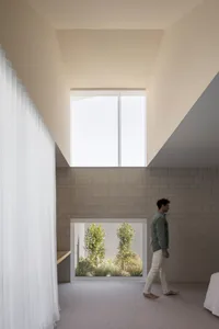 極簡風格的住宅，擁有混凝土牆面與挑高天花板，設有大型窗戶可眺望綠意空間。