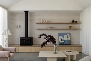 Modern living room with cement brick accent wall, floating shelves, and minimalistic furniture.
