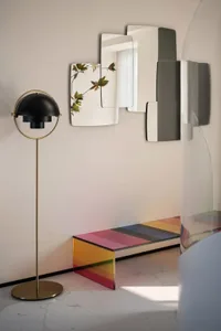 Modern living room featuring a multicolored glass coffee table with geometric patterns, a standing lamp with a spherical shad