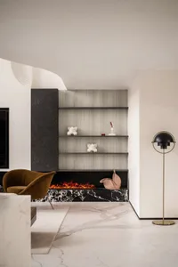 Modern living room featuring a marble fireplace with a warm fire burning.