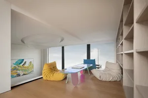 Modern living room with wood flooring, glass coffee table, and colorful sofas.