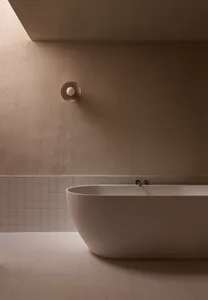 A minimalist bathroom with a freestanding bathtub and concrete tiles on the lower part of the wall.