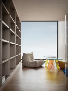 A modern minimalist living room with a wooden floor and large window.