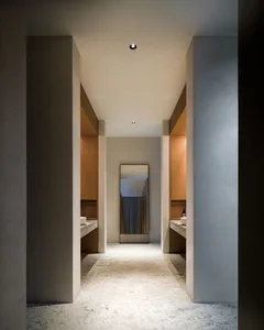 A minimalist bathroom with concrete flooring, wooden cabinets, and a large mirror.