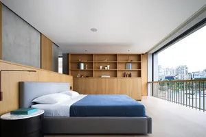 A modern bedroom featuring a large bed, wooden shelves, and a view of the cityscape.