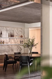 A modern dining room featuring a round table with a marble top, surrounded by black chairs, and a marble backsplash.
