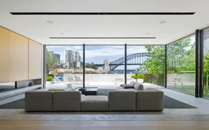 Modern living room featuring a minimalist design with large glass windows and concrete floor.