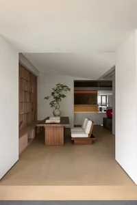 A modern minimalist living room with a wooden floor, furniture, and shelves.