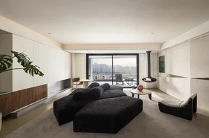 A minimalist living space with a black, textured sofa, a round coffee table, and a modern fireplace.