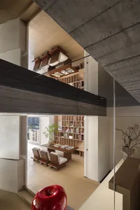 An image of a modern office space with exposed concrete walls and glass walls. The office features a wooden bookshelf filled 