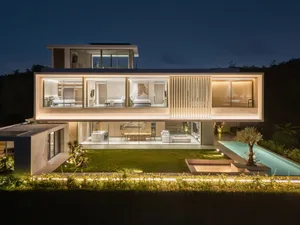 A modern residential space featuring glass, marble, and concrete materials at night.