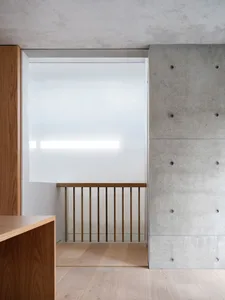 Contemporary interior design featuring a concrete wall, brass banister, and oak flooring.
