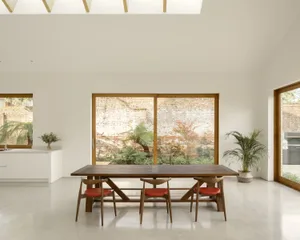 A minimalist dining room with a wooden table and red chairs.