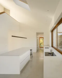 Modern minimalist kitchen with concrete flooring, marble countertops, and a waterfall island.