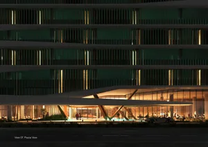 A modern hotel facade at night with metal cladding and glass columns.