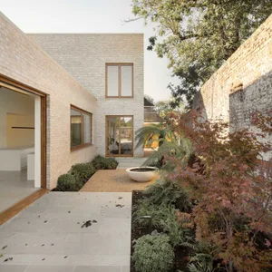 A modern house with a brick exterior, featuring large windows and a clean, minimalist design.