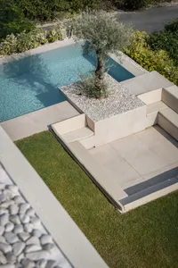 Modern poolside concrete furniture featuring a tree planter in a contemporary outdoor lounge area.