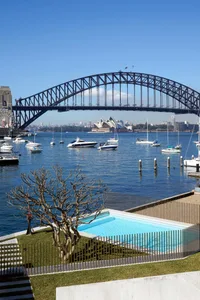 A view of a cityscape featuring a metal bridge over a body of water with several boats.