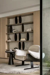 A minimalist living area featuring a white leather armchair, a small round side table with a glass drink container, and a bui