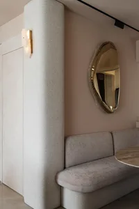 Modern interior design featuring a textured fabric sofa with a round wooden table and a unique, modern light fixture in the b