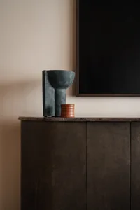 A modern cabinet with a stone countertop and a black framed mirror above it.