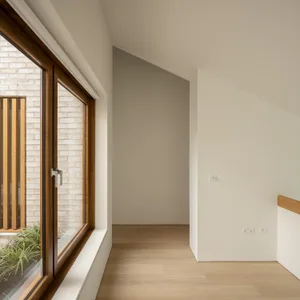 Minimalist residential interior with natural light, white walls, and wooden flooring and doors.