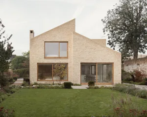 A modern residential brick house with large windows and a landscaped garden.
