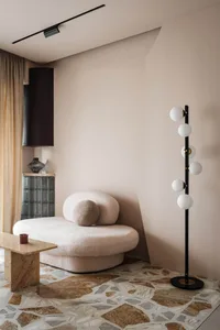 A stylish living room with a plush, rounded sofa and a geometric, terrazzo-patterned floor.