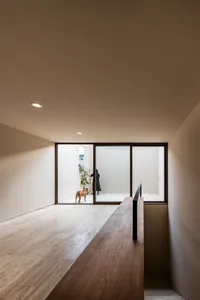 A modern interior with wooden flooring, minimalist design, and a dog in a doorway.