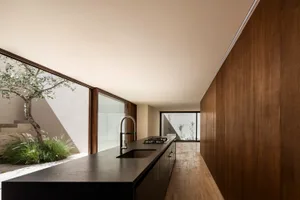Modern kitchen with black countertops and wooden cabinets, featuring a sink and stove.
