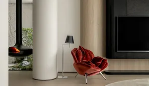 A modern living room featuring a red velvet chair, wooden column, and carpet.