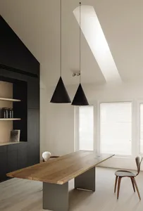 A minimalist dining room features a wooden table with metal legs, pendant lights, and a skylight.