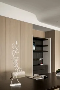 A modern minimalist office space featuring wooden shelves and a sleek desk with a sculpture and magazine on top.