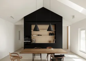 Modern black and white kitchen dining space with wooden table, black pendant lights, black and wooden shelves, and minimalist