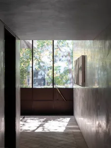 A modern interior space with concrete walls and a large window showcasing an outdoor view with trees.