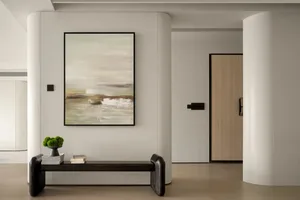 Modern white minimalist residential entryway with abstract painting and wooden bench.