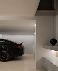 Modern garage interior with a sleek black car, concrete flooring, and minimalist design.