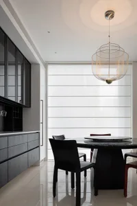 Modern kitchen interior featuring a round table with a marble top and black chairs, illuminated by a hanging lamp with a uniq