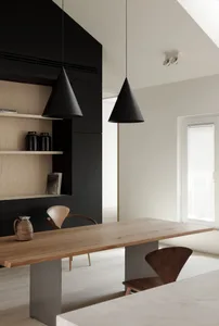 A minimalist interior design featuring a wooden dining table and black pendant lights.