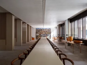 Modern restaurant interior featuring long wooden tables, ceramic sculptures, and a large mural depicting various animals.