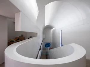 Modern white interior featuring a curved concrete staircase.