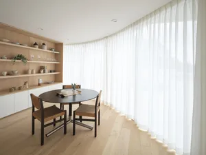 Minimalist dining room featuring wooden table and chairs with cotton blend curtains