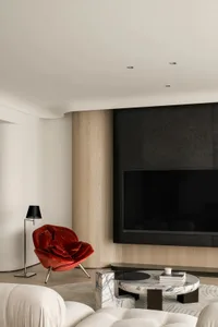 A minimalist living room featuring a red velvet armchair, a marble coffee table, and wooden walls
