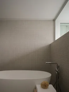 A minimalist bathroom with tiled walls and a freestanding bathtub.