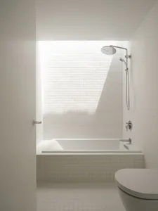 A modern minimalist bathroom featuring white tiled walls, a concrete base surrounding a bathtub, and a shower head mounted on