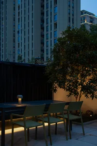 Modern outdoor patio with concrete flooring, illuminated by warm lighting fixtures.