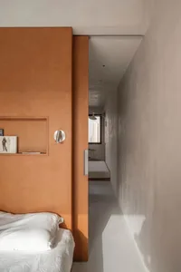 Minimalist bedroom featuring an orange wood headboard with a white bedspread