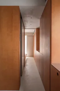 A minimalist hallway with wooden walls and a white floor.